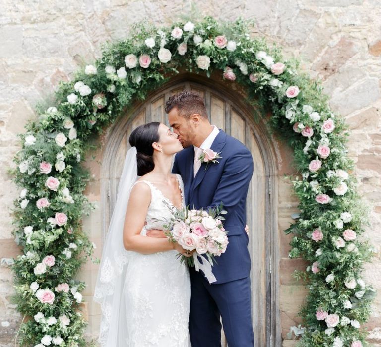 Bride and groom portrait in front of a floral arch