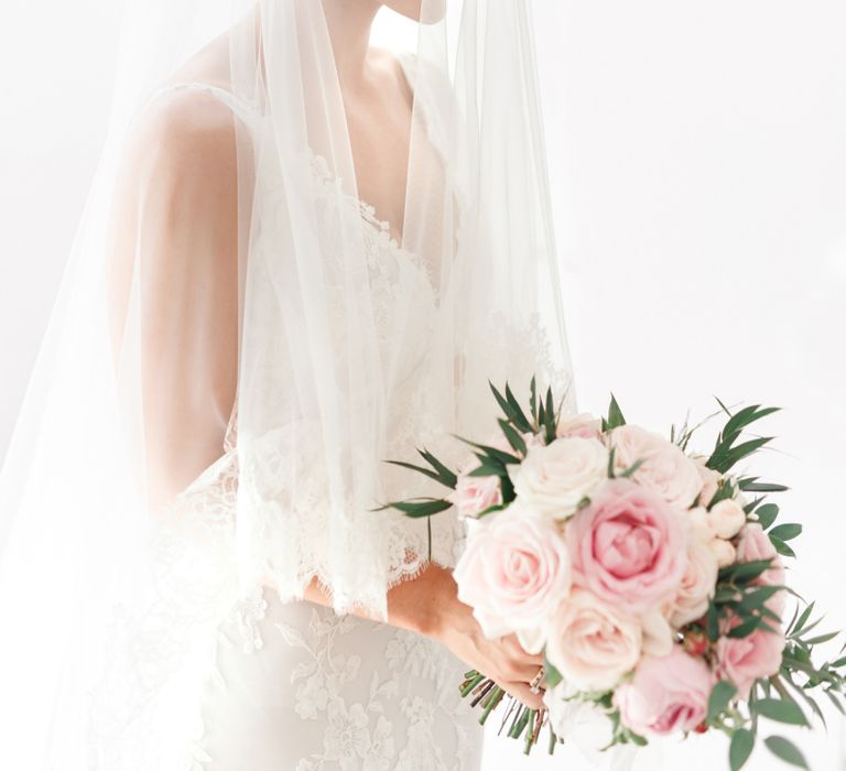 Bride holding a pink bouquet with a wedding veil