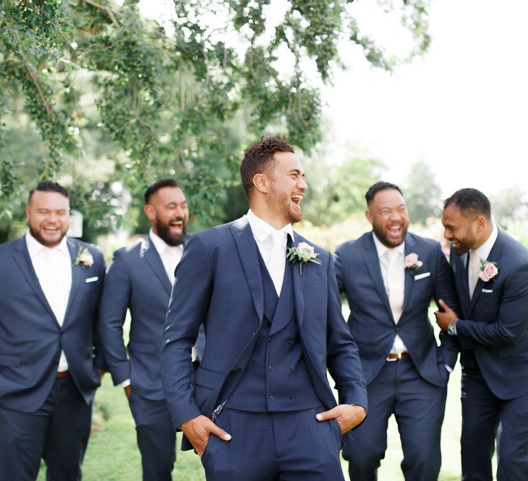 Groomsmen in navy suits laughing together