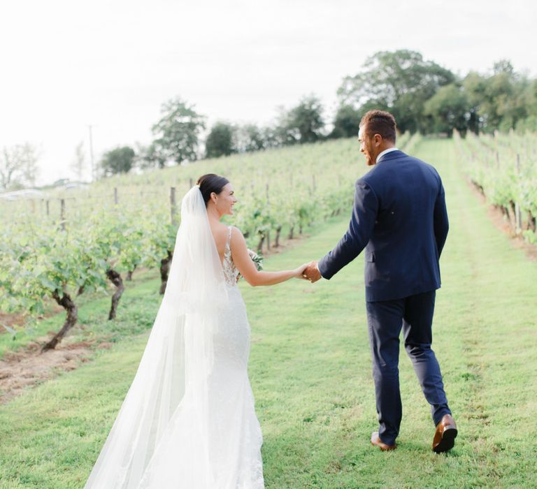 Bride and groom walking through the vineyard at Coddington