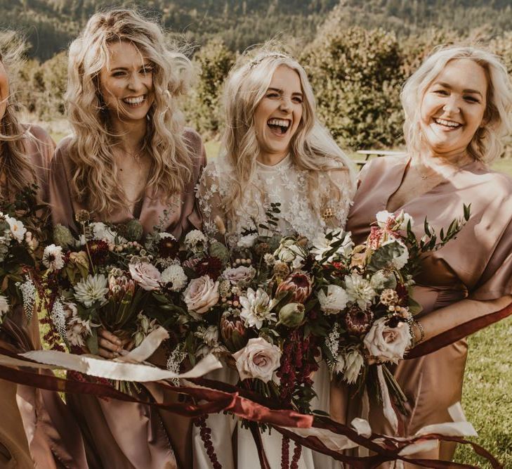 Bridesmaids in blush dresses with floral bouquets