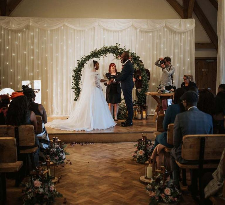 Bride and groom exchanging vows in front of their floral moon gate