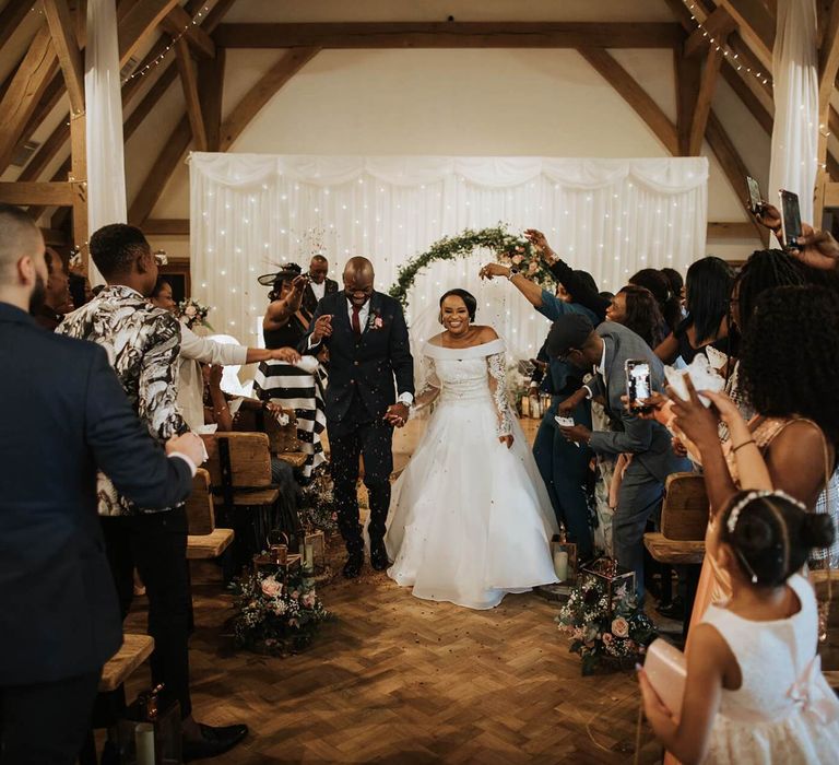 Bride and groom walking up the aisle as husband and wife at The Old Kent Barn