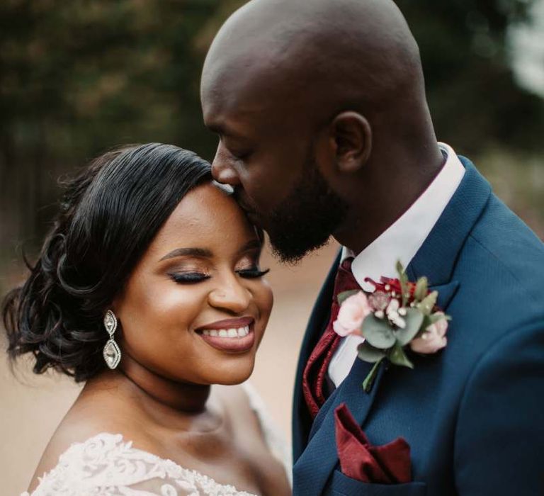 Groom kissing his brides forehead