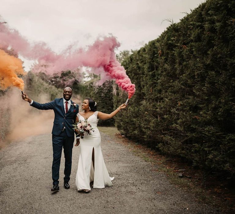 Bride and groom holding smoke flares at The Old Kent Barn