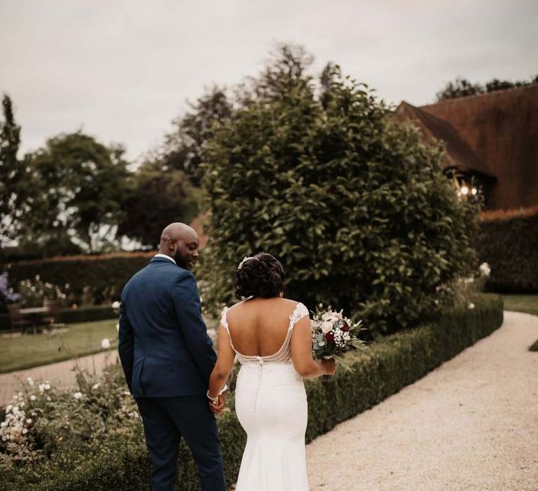 Bride and groom walking through the grounds at The Old Kent Barn wedding venue