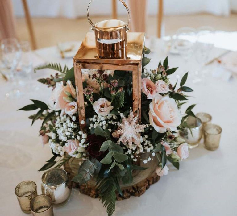 Lantern and floral centrepiece on tree slice at The Old Kent Barn wedding