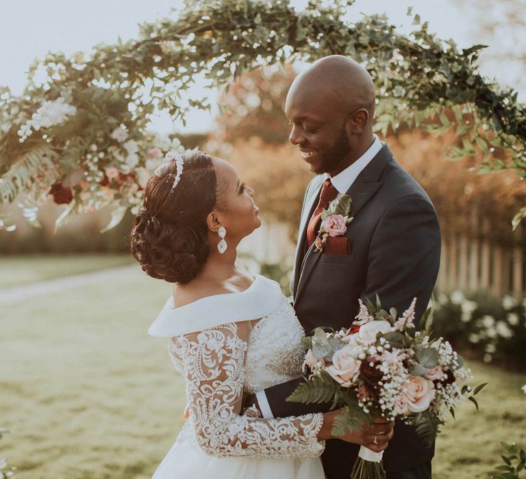 Bride and groom golden hour portrait in front of a floral moon gate  at The Old Kent Barn wedding