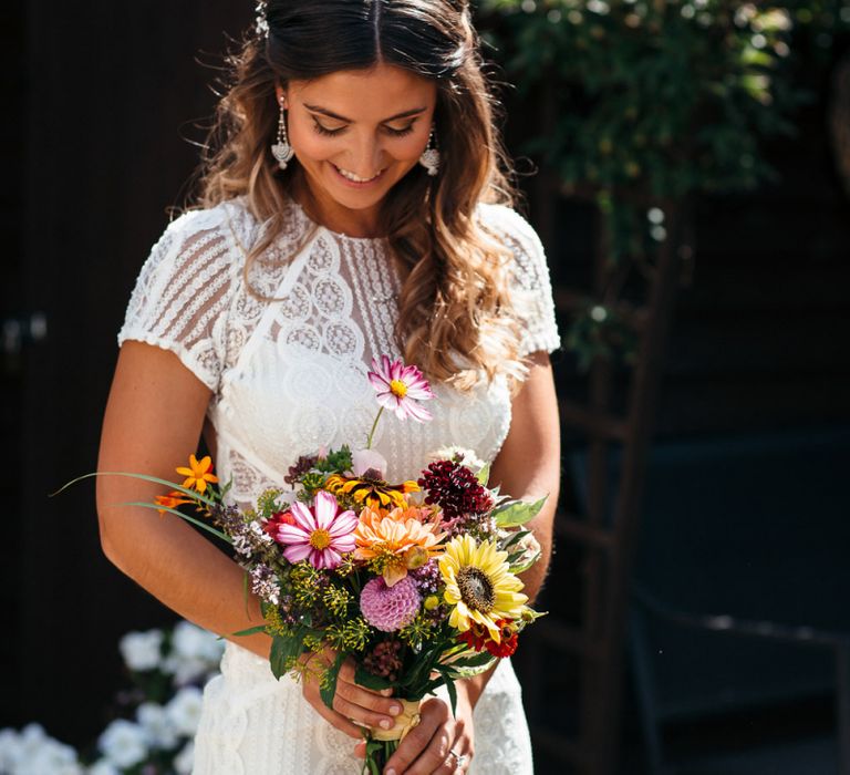 Bride in Lenora Dress by Wtoo Watters with Lace Cap Sleeves and Keyhole Back | Colourful Bridal Bouquet with Sunflowers and Yellow Trailing Ribbon | Macrame Decor, Vintage Caravan Photobooth and Five-Tier Naked Wedding Cake for Boho Wedding in Woodlands | Freckle Photography