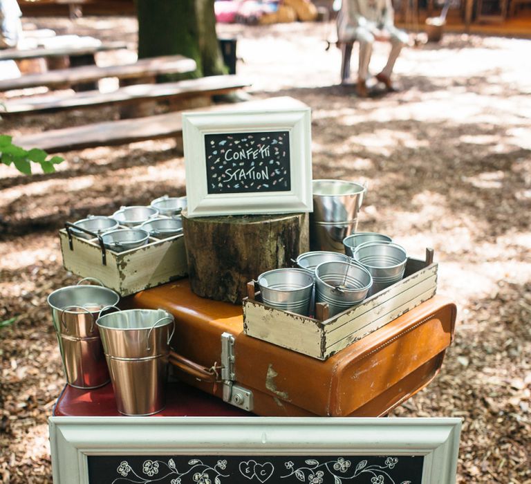 Chalkboard Pick A Seat Not A Side Wedding Sign | Metal Confetti  Buckets | Confetti Station | Vintage Suitcase | Lila's Wood Wedding Venue | Macrame Decor, Vintage Caravan Photobooth and Five-Tier Naked Wedding Cake for Boho Wedding in Woodlands | Freckle Photography