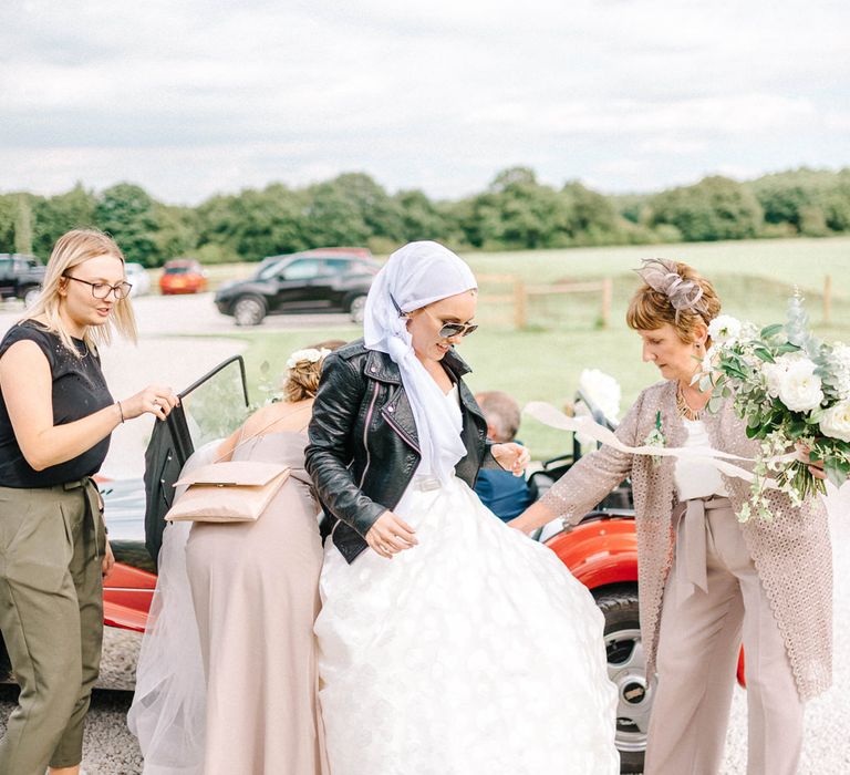 Red Kit Car Decorated with Ribbon | Arrival of the Bride | Strapless Sassi Holford Ballgown Wedding Dress with Belt | Bride in Leather Jacket, Headscarf and Sunglasses | Mother of the Bride in Grey Trouser Suit | Hazel Gap Barn Wedding with Bride Arriving by Kit Car | Sarah-Jane Ethan Photography