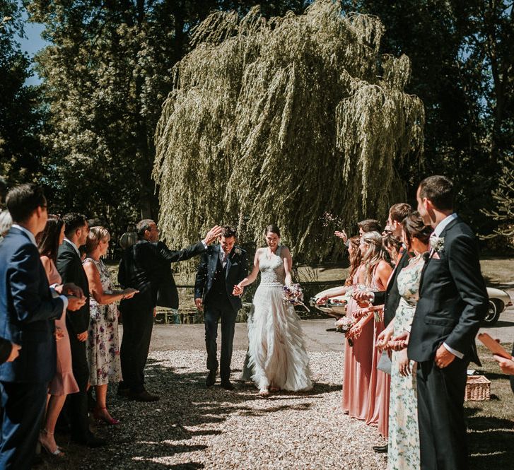 Confetti Moment with Bride in Pronovias Danaia Wedding Dress and Groom in Navy Moss Bros. Suit