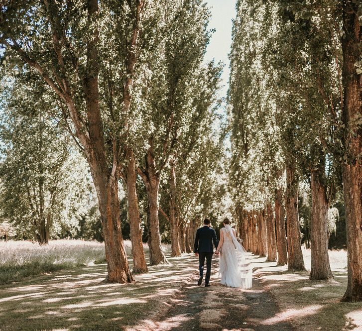 Bride in Pronovias Danaia Wedding Dress and Groom in Moss Bros. Suit  Walking Through The Woods