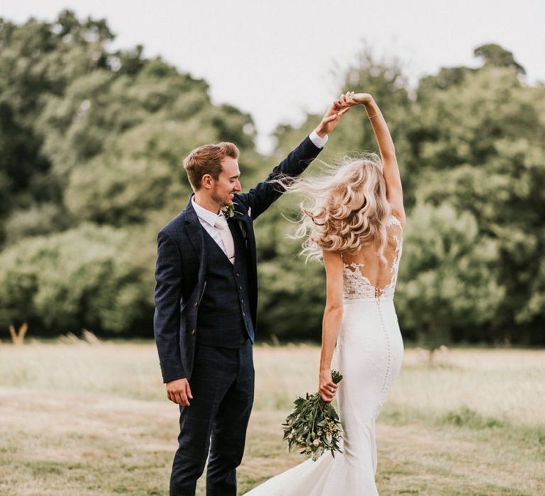 Groom in Navy Check Moss Bros Suit Twirling Bride in Vicenta Pronovias Wedding Dress