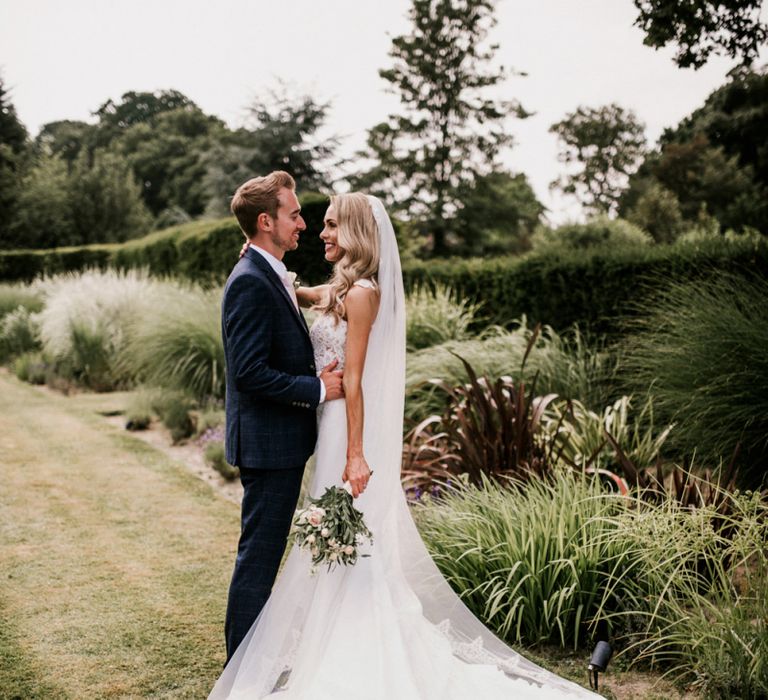 Bride in Vicenta Pronovias Wedding Dress and Groom in Navy Check Moss Bros Suit Hugging