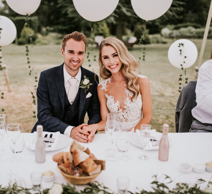 Bride in Vicenta Pronovias Wedding Dress and Groom in Navy Check Moss Bros Suit at Wedding Breakfast