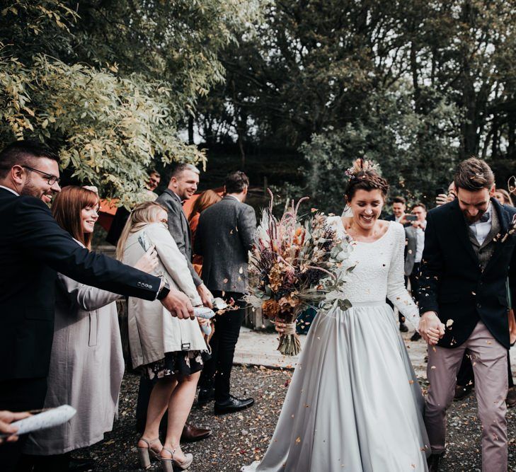 Confetti Moment in the Woods with Bride in Silver Skirt and Groom in Pink Chinos and Navy Blazer