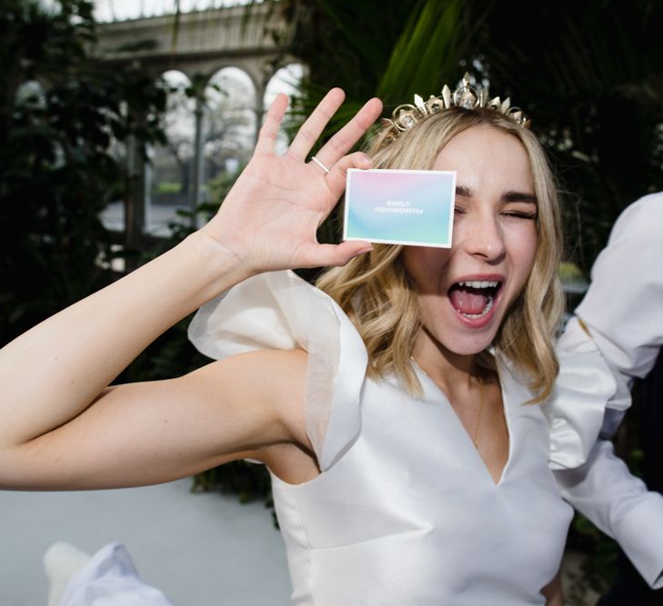 Bride wears crown and holds up bright place name card