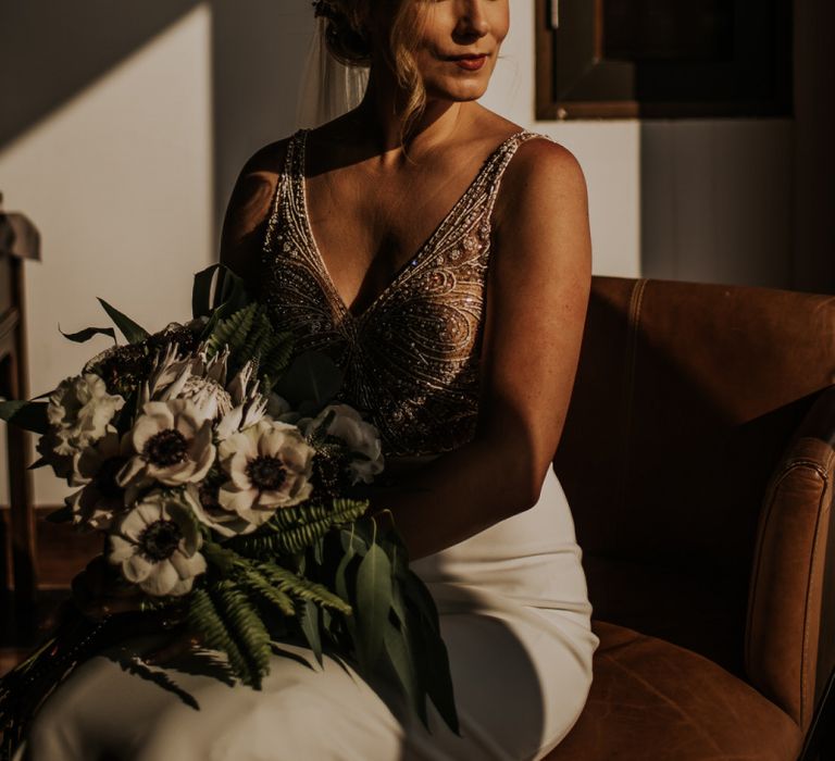 Bride in beaded bodysuit with bouquet and updo