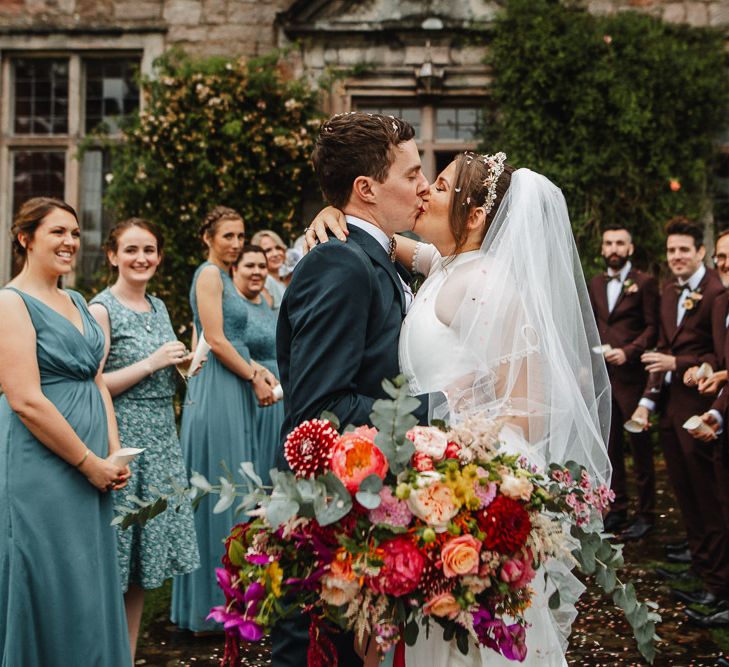 Bride and Groom Kissing Whilst Holding a Pink Wedding Bouquet