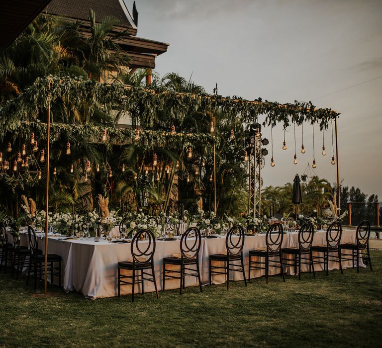 Stunning intimate wedding set up with hanging light installation and foliage