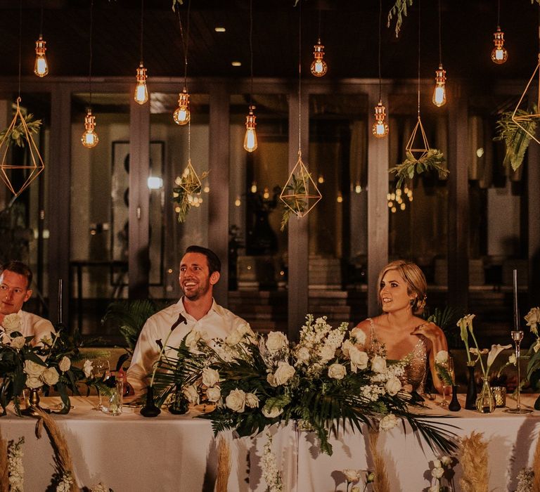 Bride and groom at intimate Thailand wedding with hanging lights and geometric decor