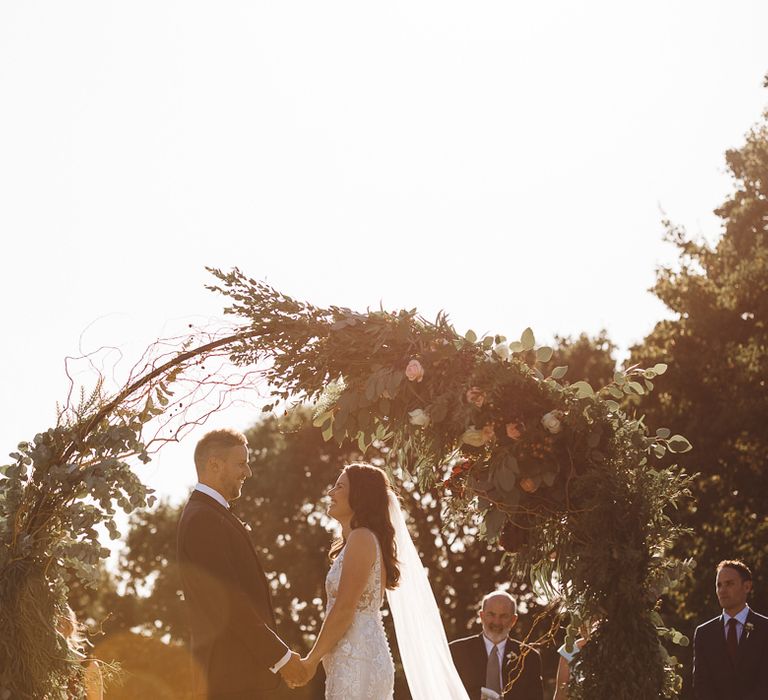 Beautiful floral and foliage hoop decor at intimate outdoor ceremony