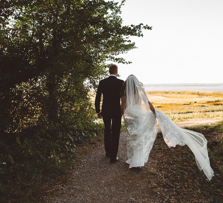 Back of brides Made With Love Bridal dress and veil at romantic outdoor wedding