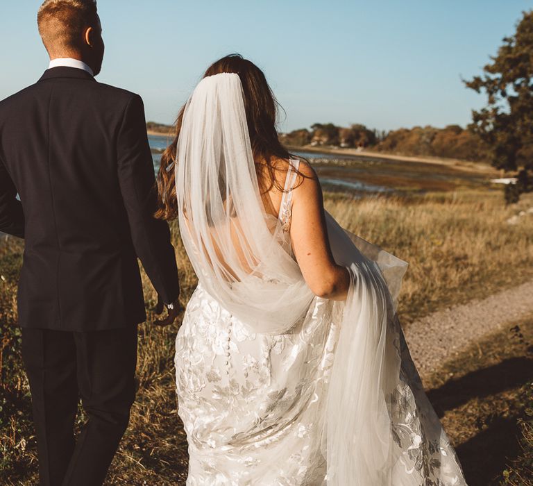 Back of brides Made With Love Bridal dress and veil at romantic outdoor wedding