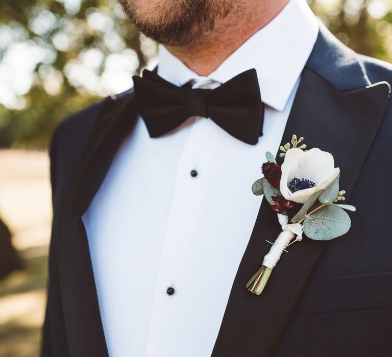 Groom wearing floral buttonhole and bow tie at Crouchers Orchards for outdoor wedding ceremony