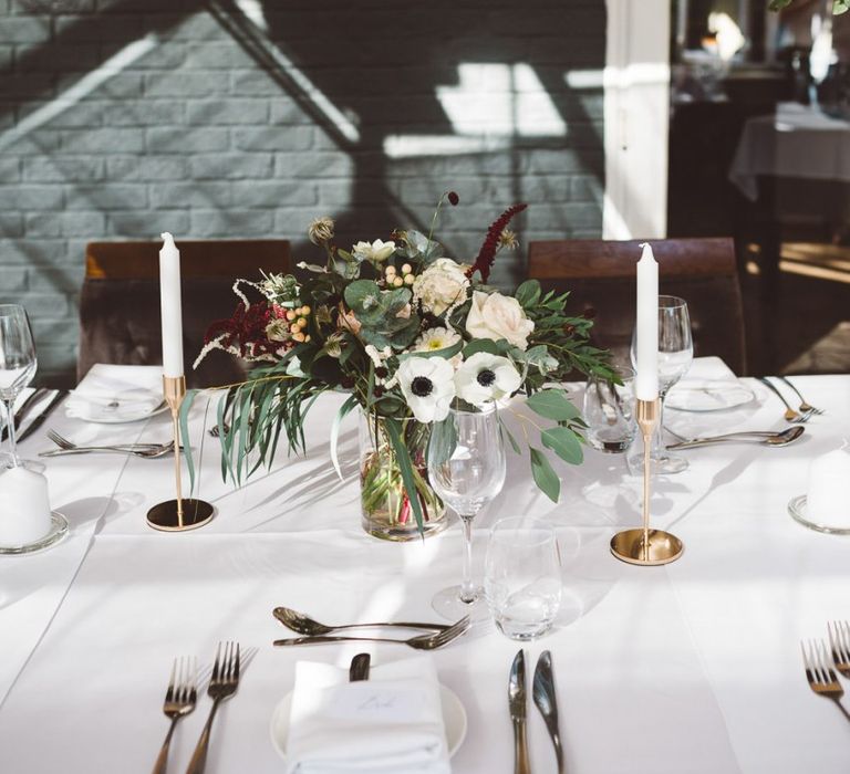 Hanging foliage and floral table arrangements styled with gold candlesticks for intimate dinner