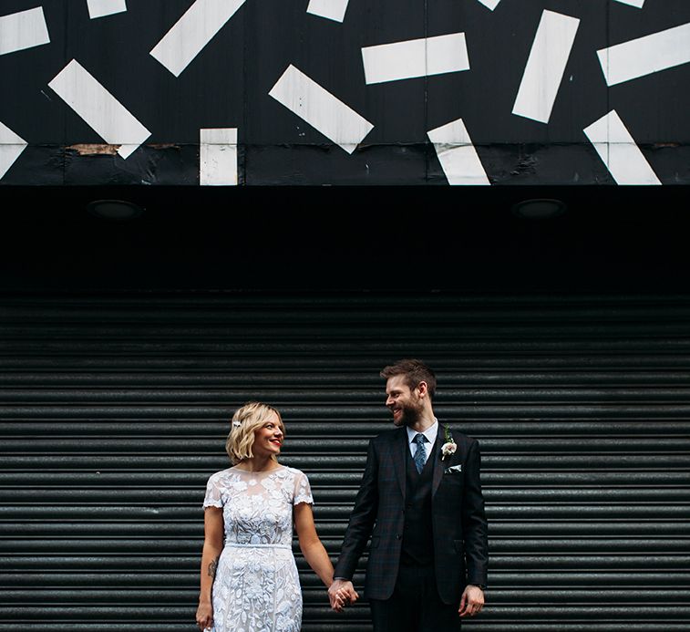 Bride in Lace Hermione De Paula Wedding Dress and Groom in Ted Baker Suit  Holding Hands