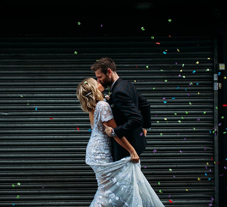 Bride in Lace Hermione De Paula Wedding Dress and Groom in Ted Baker Suit  Kissing with Confetti Bomb Going Off