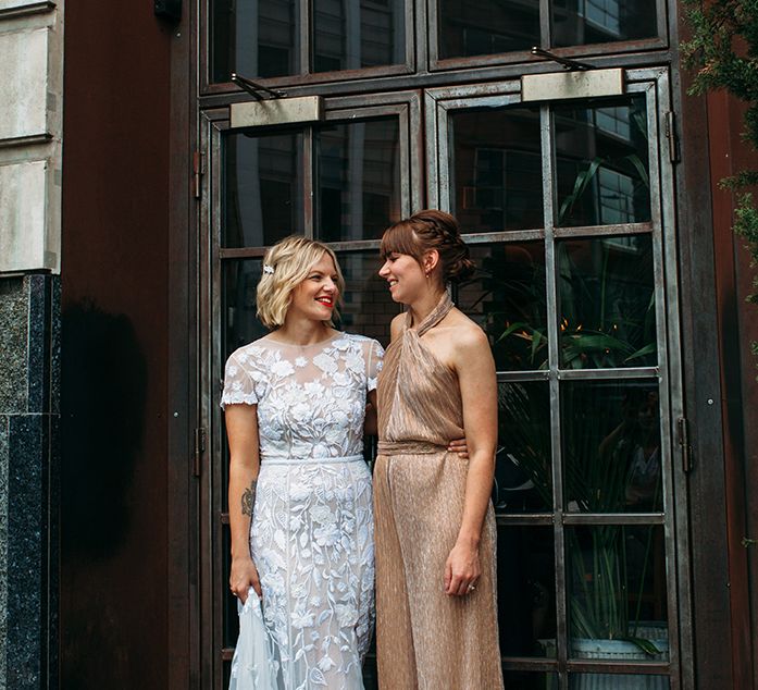 Bride in Lace Hermione De Paula Wedding Dress and Bridesmaid in Metallic The Jestset Diaries Avalon Jumpsuit  via ASOS