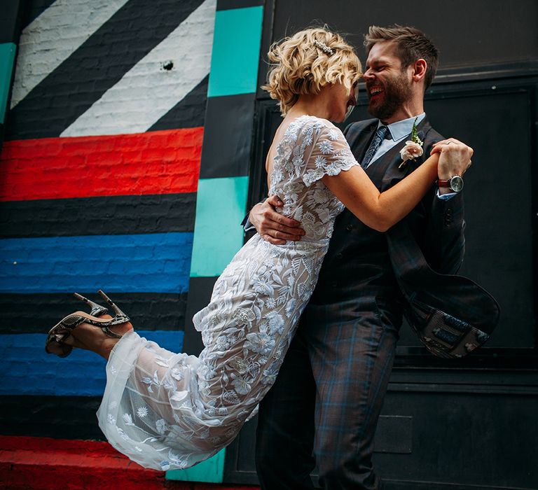 Groom in Ted Baker Suit Swinging His Bride Around in Lace Hermione De Paula Wedding Dress