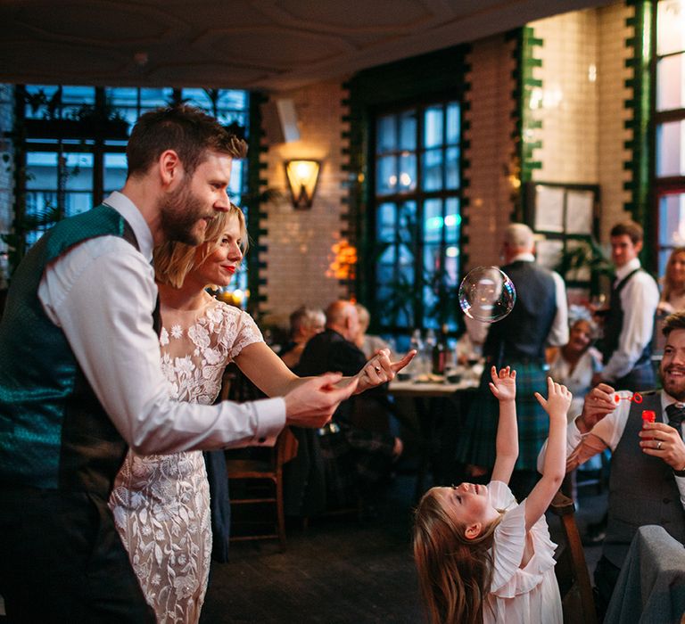 Flower Girl and Bride and Groom Catching Bubbles Together