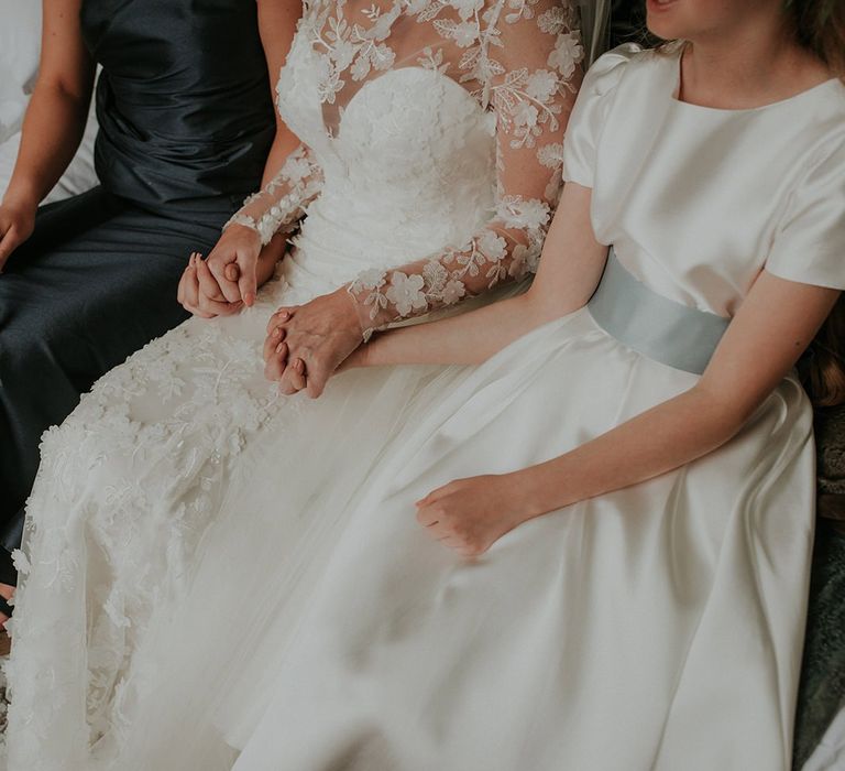 Bride in Suzanne Neville wedding dress holds hands with bridesmaids