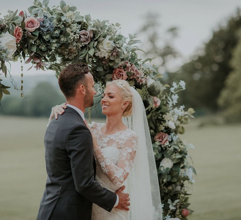 Bride and groom share a moment in front of floral moon gate