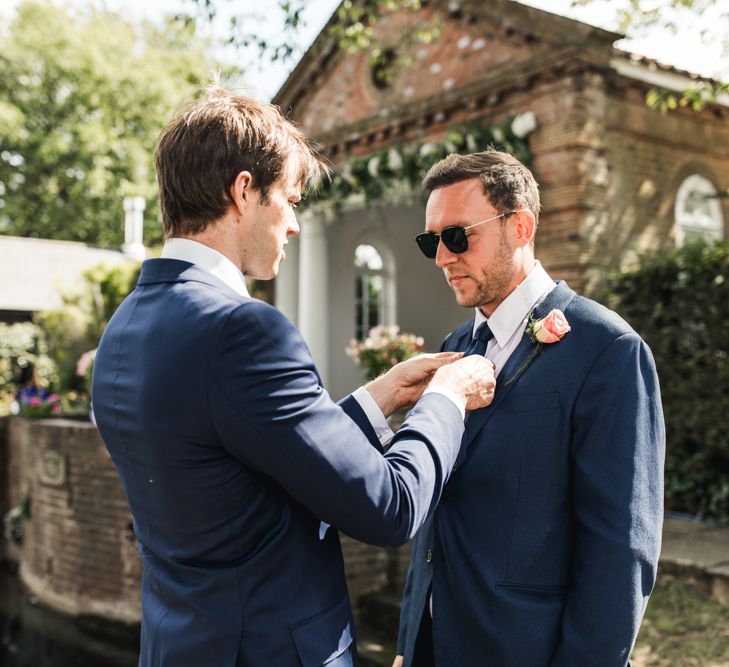 Groomsmen putting on the grooms tie