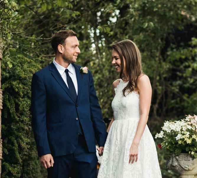 Bride in lace tea dress and groom in navy suit for micro wedding