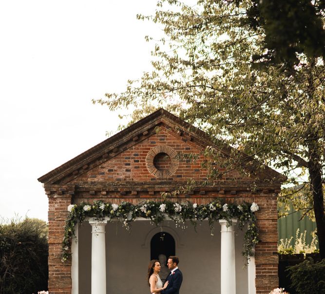 Bride and groom portrait in the temple by the pond at Micklefield Hall