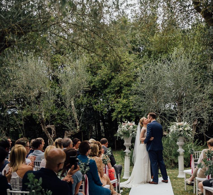 Outdoor ceremony in the Castle grounds. Destination wedding in Italy. Featuring RMW The List recommended suppliers Wiskow &amp; White and Red on Blonde. Rue de Seine wedding gown with deep red chianti bridesmaid Rewritten dresses.