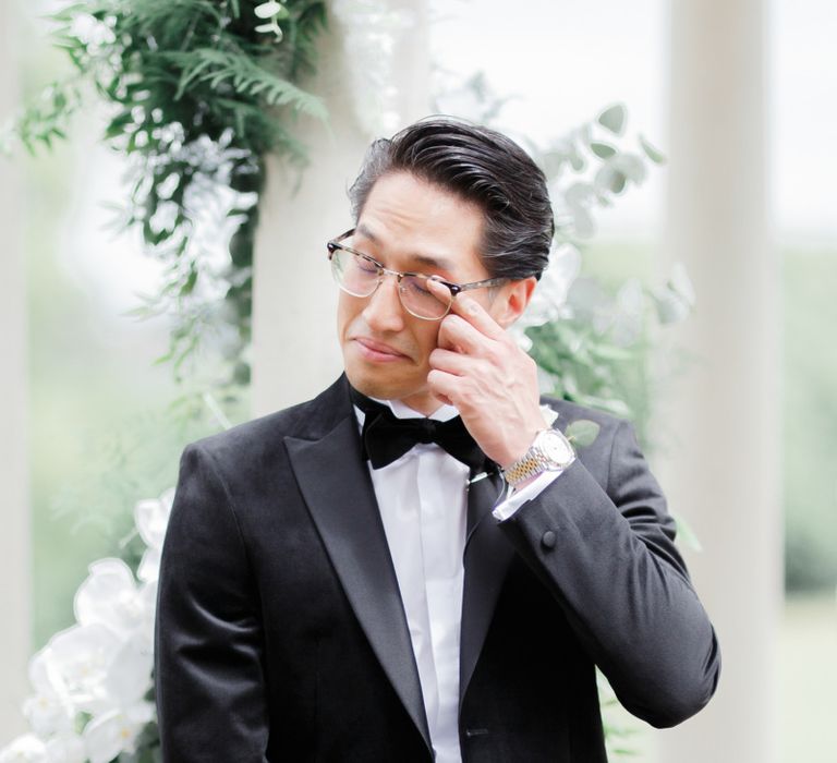 Emotional groom in black tuxedo at Froyle Park wedding ceremony