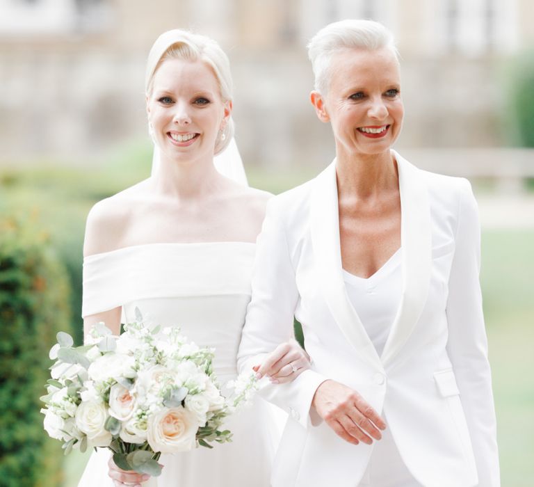 Mother of the bride in white suit and bride in Mori Lee off the shoulder wedding dress