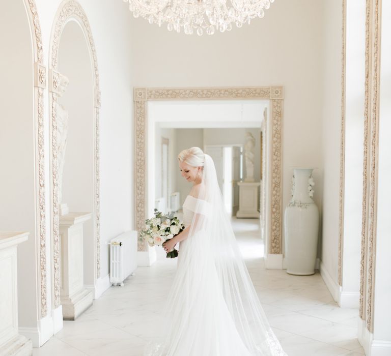 Bride in Mori Lee wedding dress and cathedral length veil standing in Froyle Park wedding venue