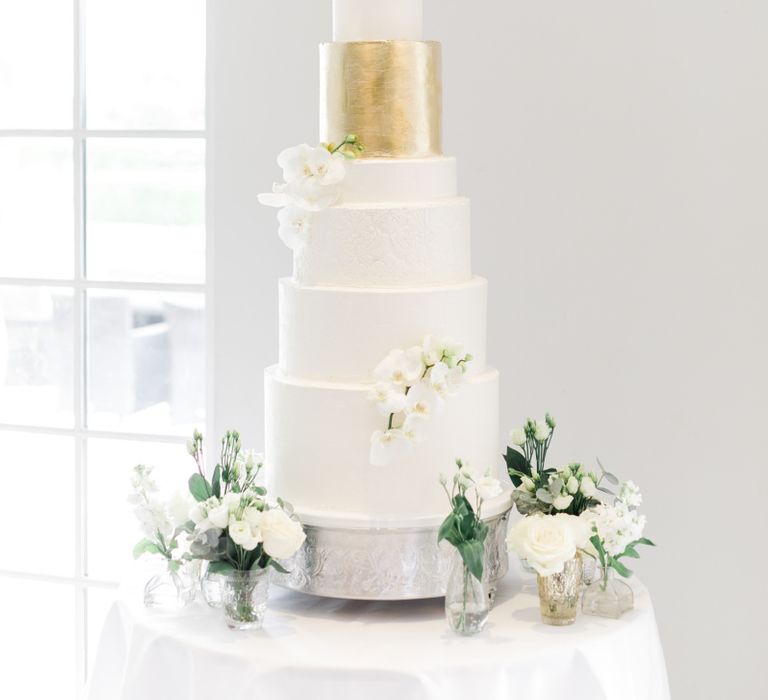 Tall wedding cake with different size layers and gold leaf detail