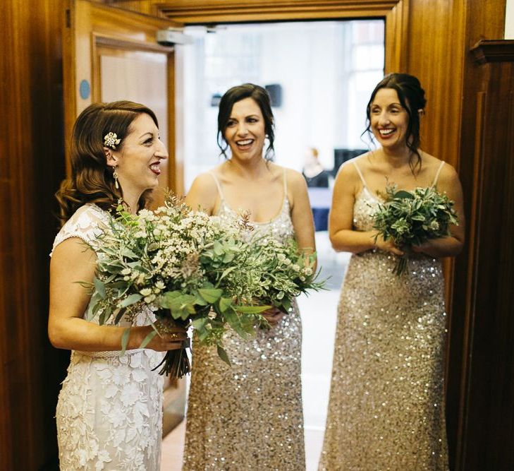 Bride wearing Phase Eight Wedding Dress and her bridesmaids wearing embellished dresses teamed with white foliage bouquets