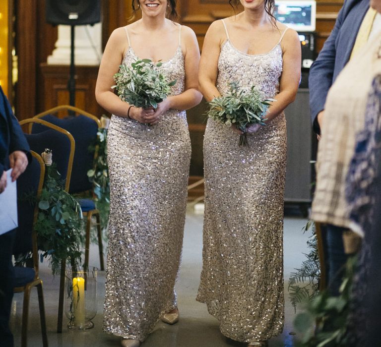 Bridesmaids wearing beautiful embellished dresses and clutching simple white foliage bouquets