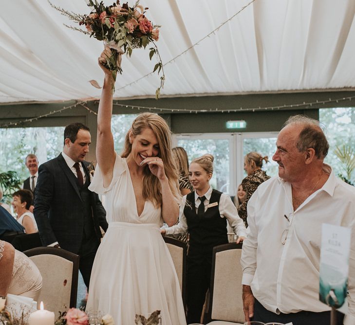 Bride in Tiered Houghton NYC Wedding Dress Holding Up Her Bouquet During The Wedding Reception