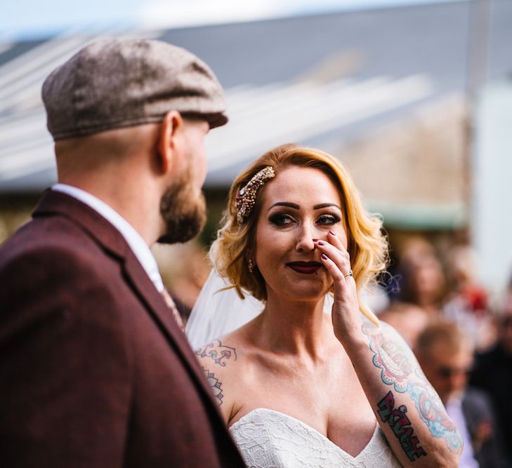 Wedding Ceremony | Bride in Strapless Sassi Holford Wedding Dress with Sweetheart Neckline | Groom in Burgundy Tweed Three Piece Suit | Edison Bulb Floral Installation at Kingsthorpe Lodge Barn Wedding | Johnny Dent Photography